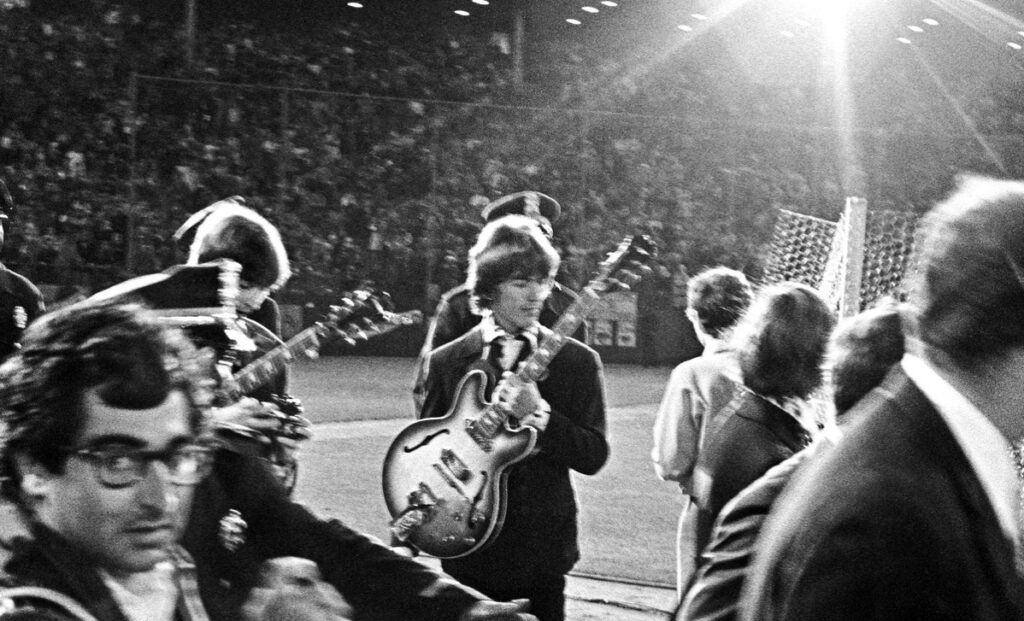George Harrison, center, and Ringo Starr, partially obscured, and the rest of The Beatles walk onto the infield of Candlestick Park, their last public concert.