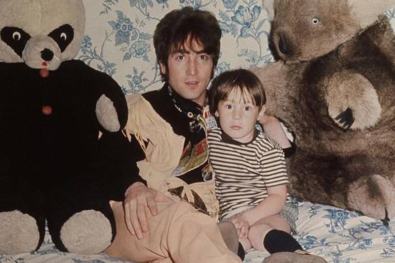 Young Julian sits on a bed with his father.