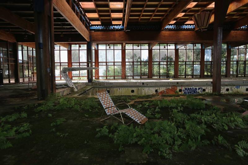 A lawn chair sits as nature takes over the indoor pool area of Grossinger's Catskill Resort Hotel