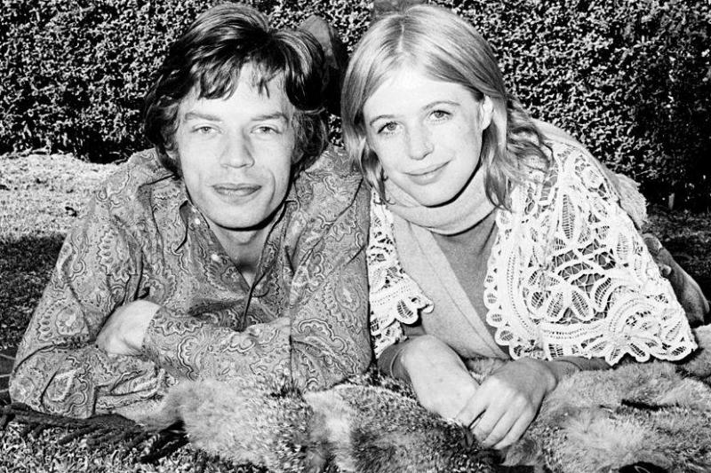 Mick and Marianne lay next to one another in a grass yard.
