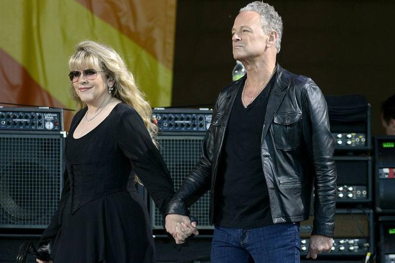 Stevie and Lindsey walk hand in hand on a stage.