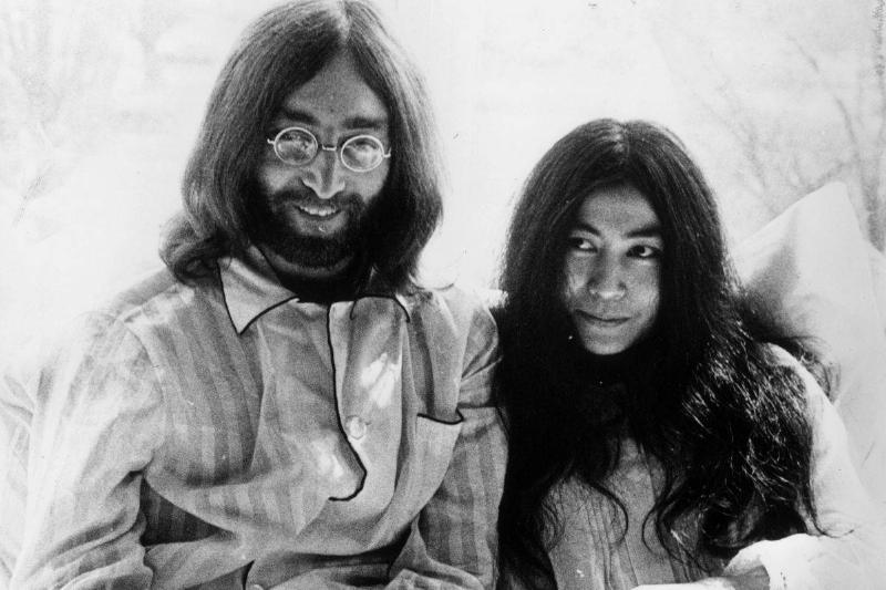 John and Yoko sit next to one another in bed.