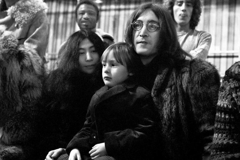 Yoko Ono smiles at young Julian, who sits on John's lap.