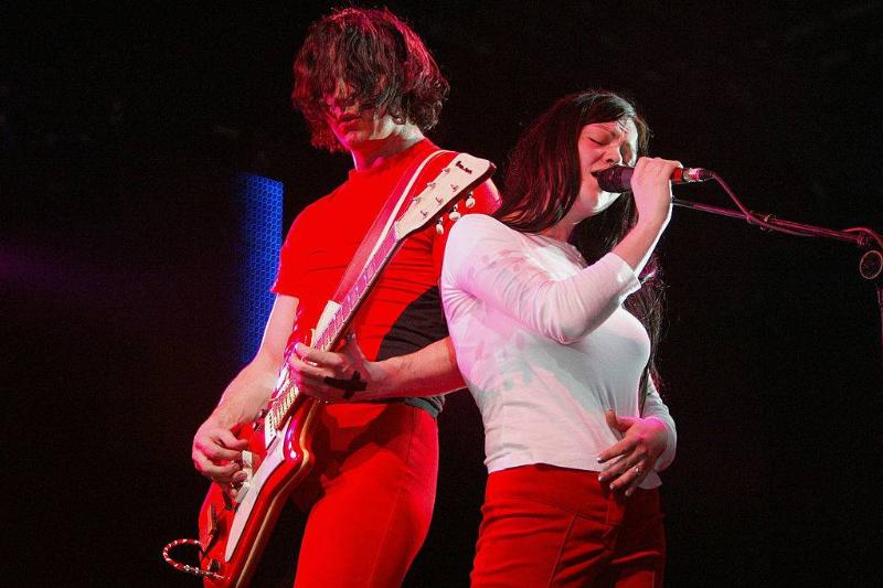 Jack plays guitar while Meg sings onstage.
