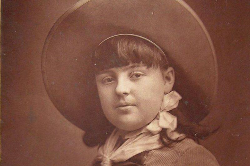 Lillian poses in a hat and cordoroy dress.