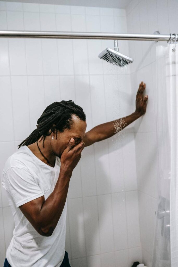 Man with hand over his face in the shower