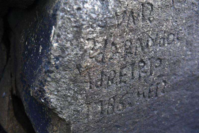 A close-up shows the inscriptions on the rock.
