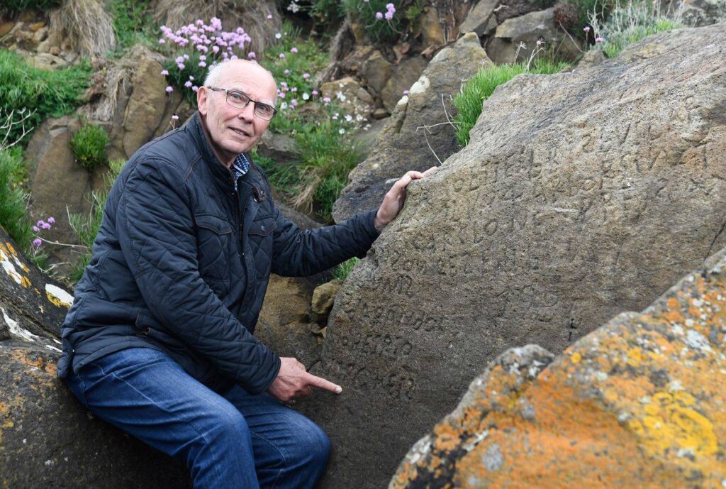 French local councillor in charge of small heritage Michel Paugam shows inscriptions composing indecipherable words on a rock.