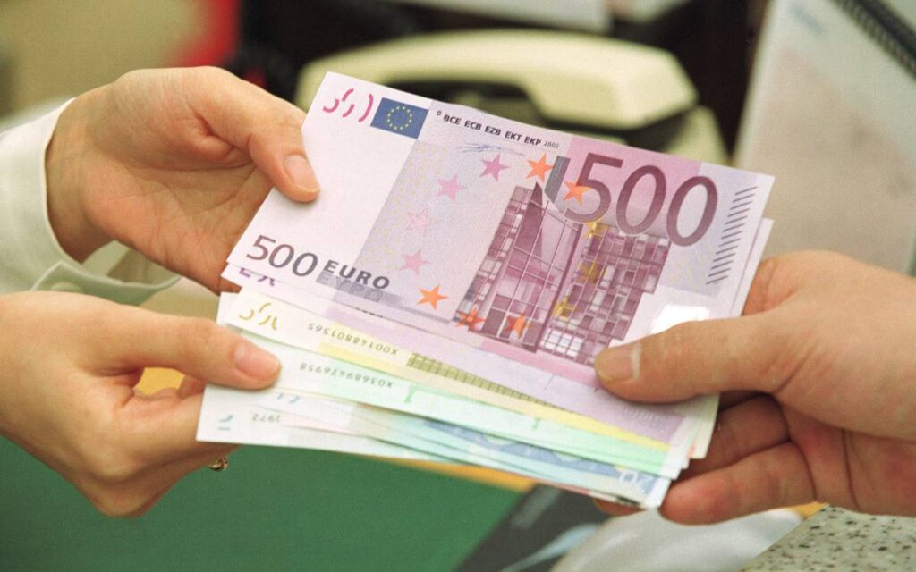 A person hands several hundred euros to another person.