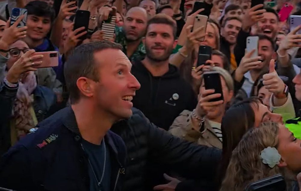 Watch Chris Martin Sing New Coldplay Song “We Pray” With Little Simz, Burna Boy, Elyanna, & Tini In The Streets Of Dublin