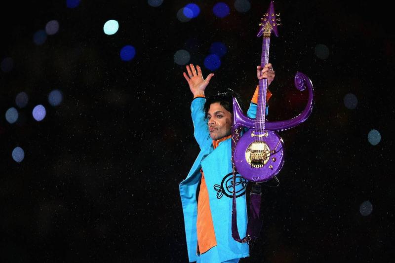 Prince holds up his symbol guitar at the super bowl half time show in 2007.